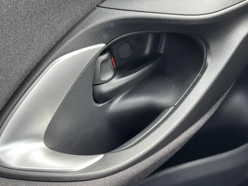 Poignée intérieure de porte côté gauche noire et argentée de la Toyota Yaris 116h Dynamic 5p MC24 blanche 2025.