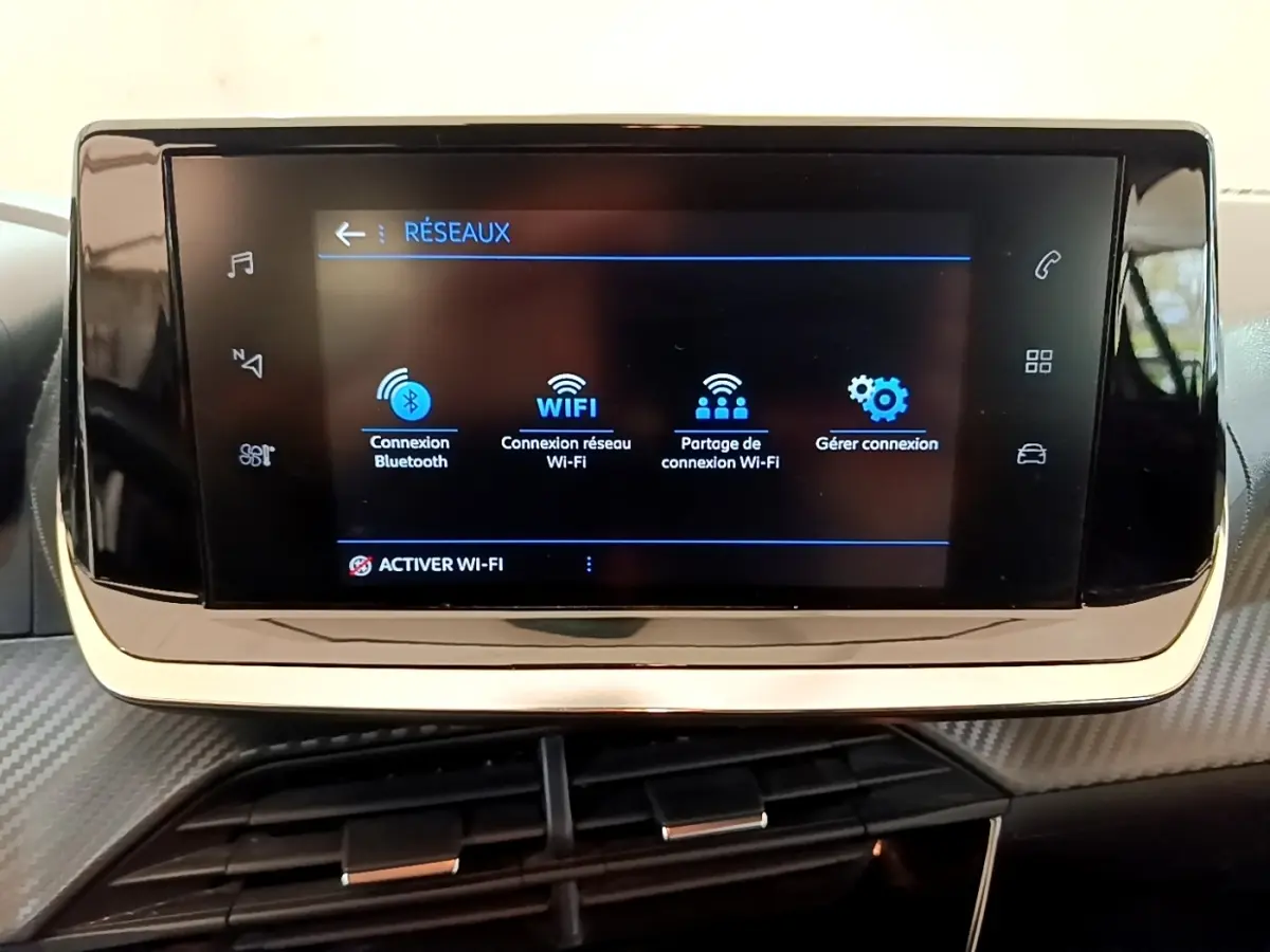 Écran tactile central du tableau de bord de la Peugeot 208 blanc, affichant les options de connexion Wi-Fi et Bluetooth.