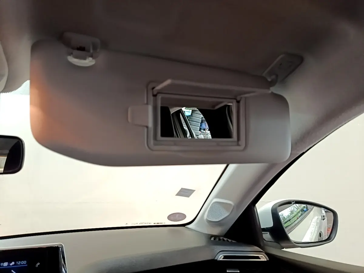 Intérieur de la Peugeot 208 blanc, vue du pare-soleil côté conducteur avec miroir de courtoisie ouvert.
