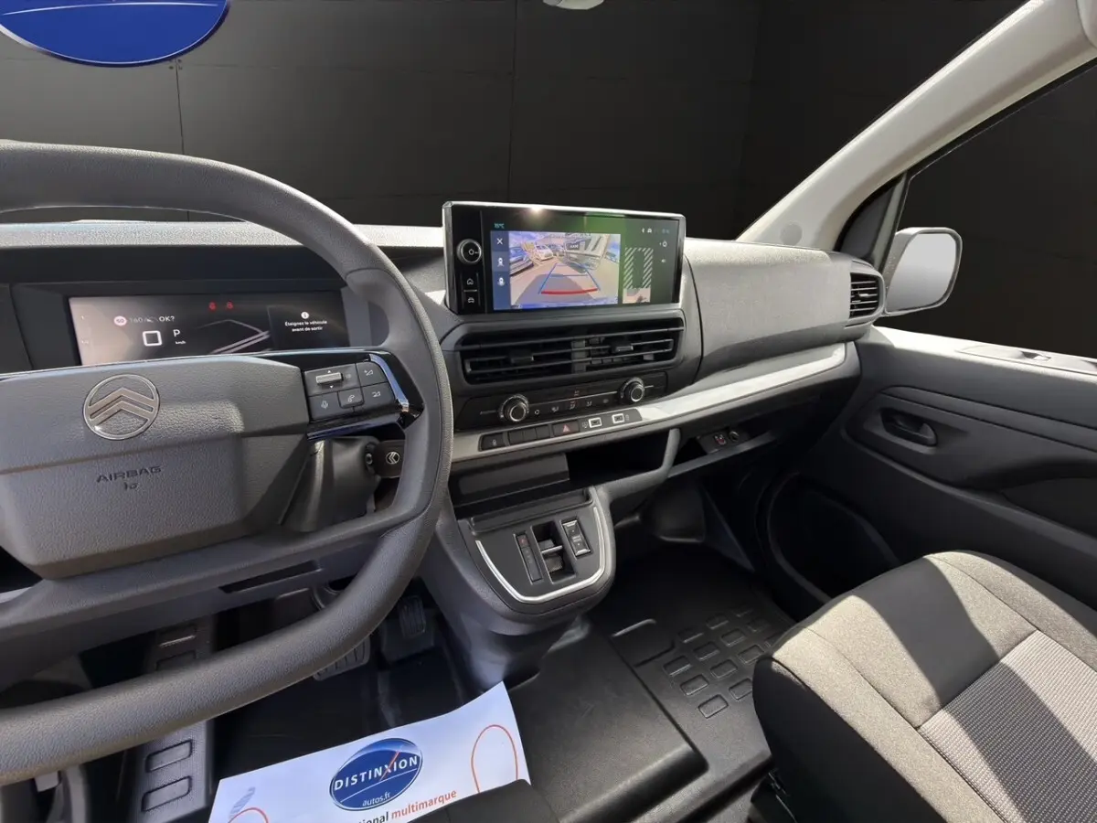 Vue intérieure côté conducteur du tableau de bord gris avec écran tactile et volant multifonctions du Citroën Jumpy gris foncé.