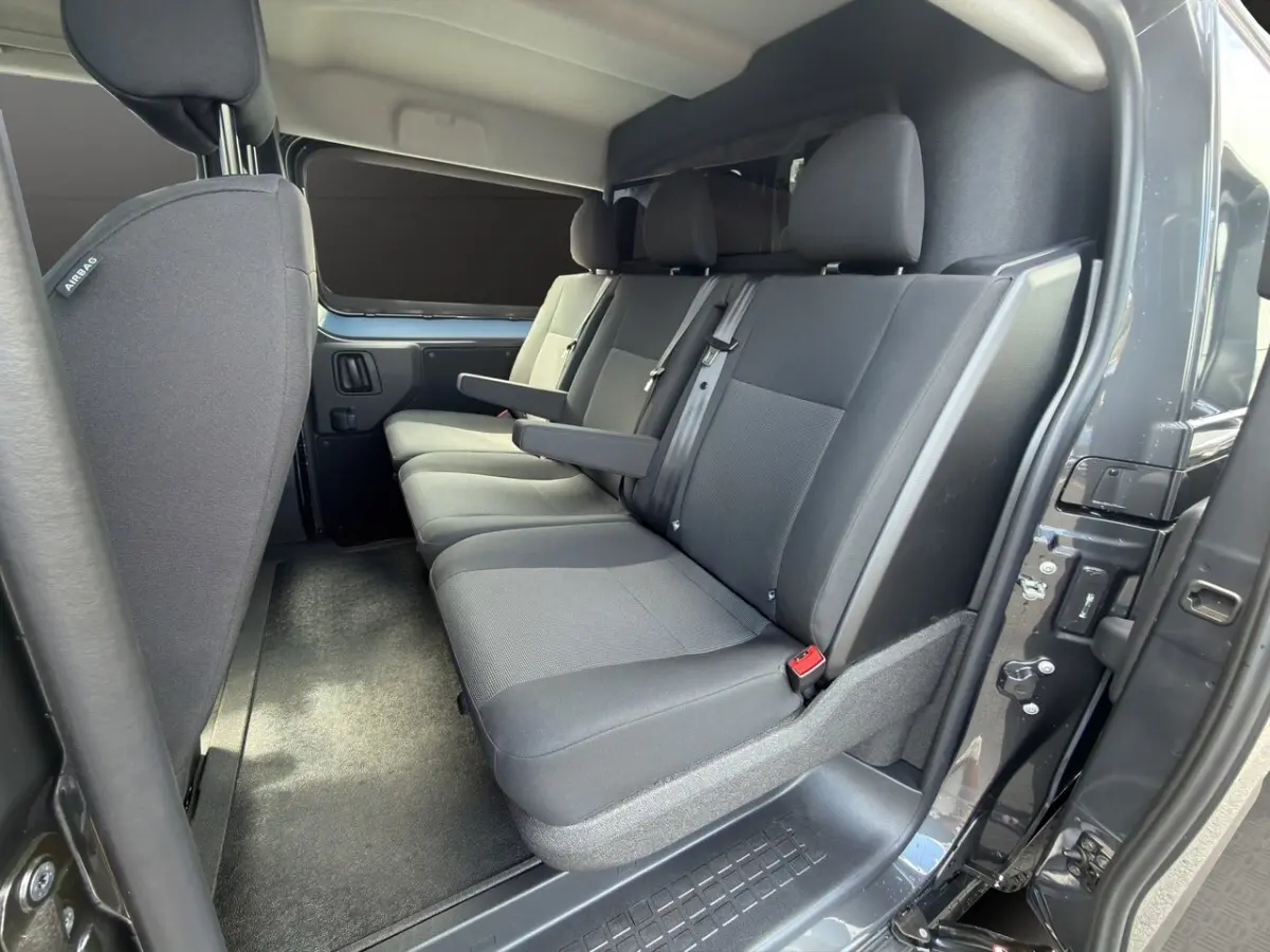 Vue intérieure côté droit sur la banquette arrière grise du Citroën Jumpy 2026 avec cloison vitrée et porte ouverte.