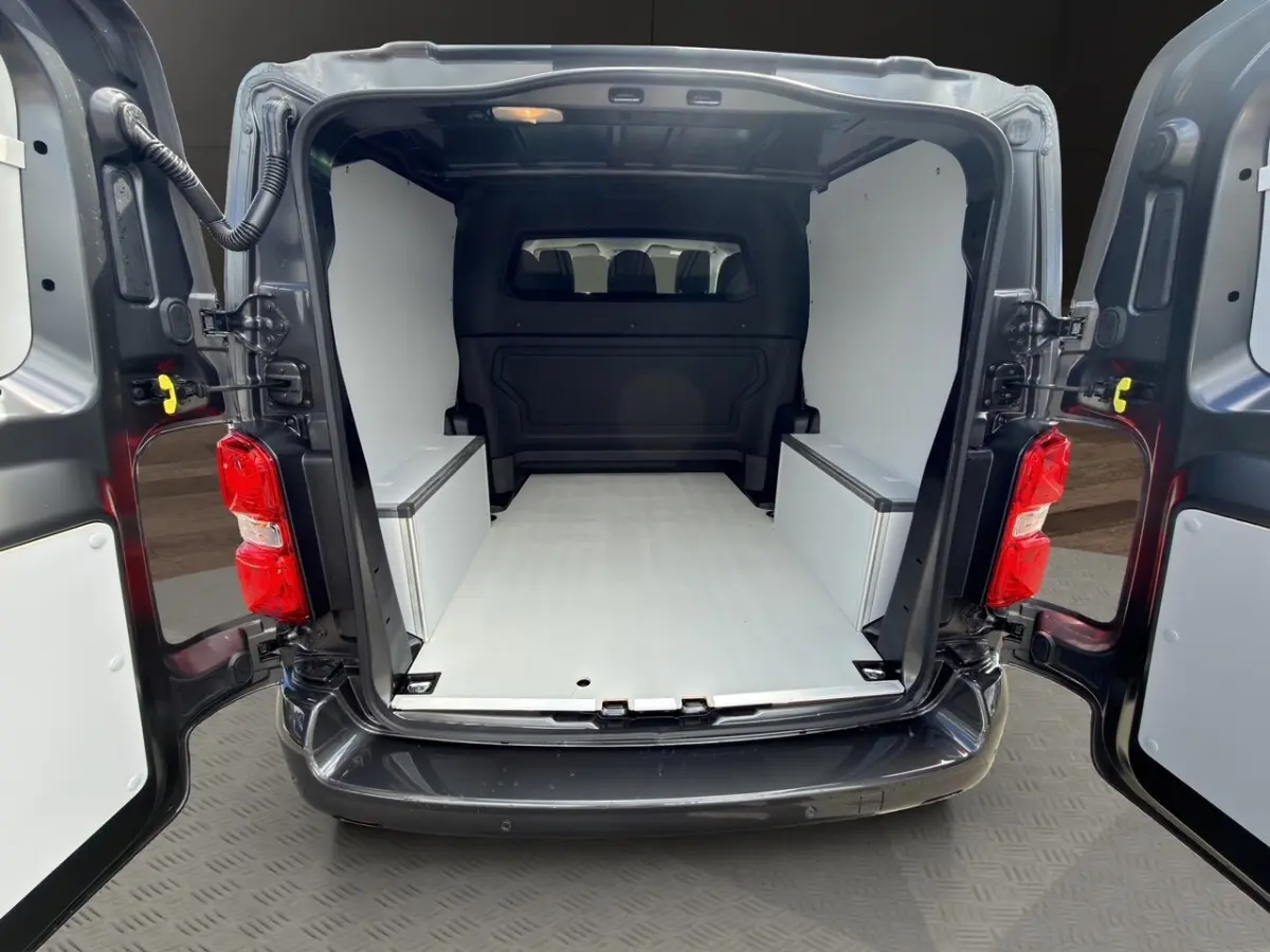 Vue arrière ouverte du Citroën Jumpy gris foncé, montrant l'espace de chargement aménagé avec parois blanches.