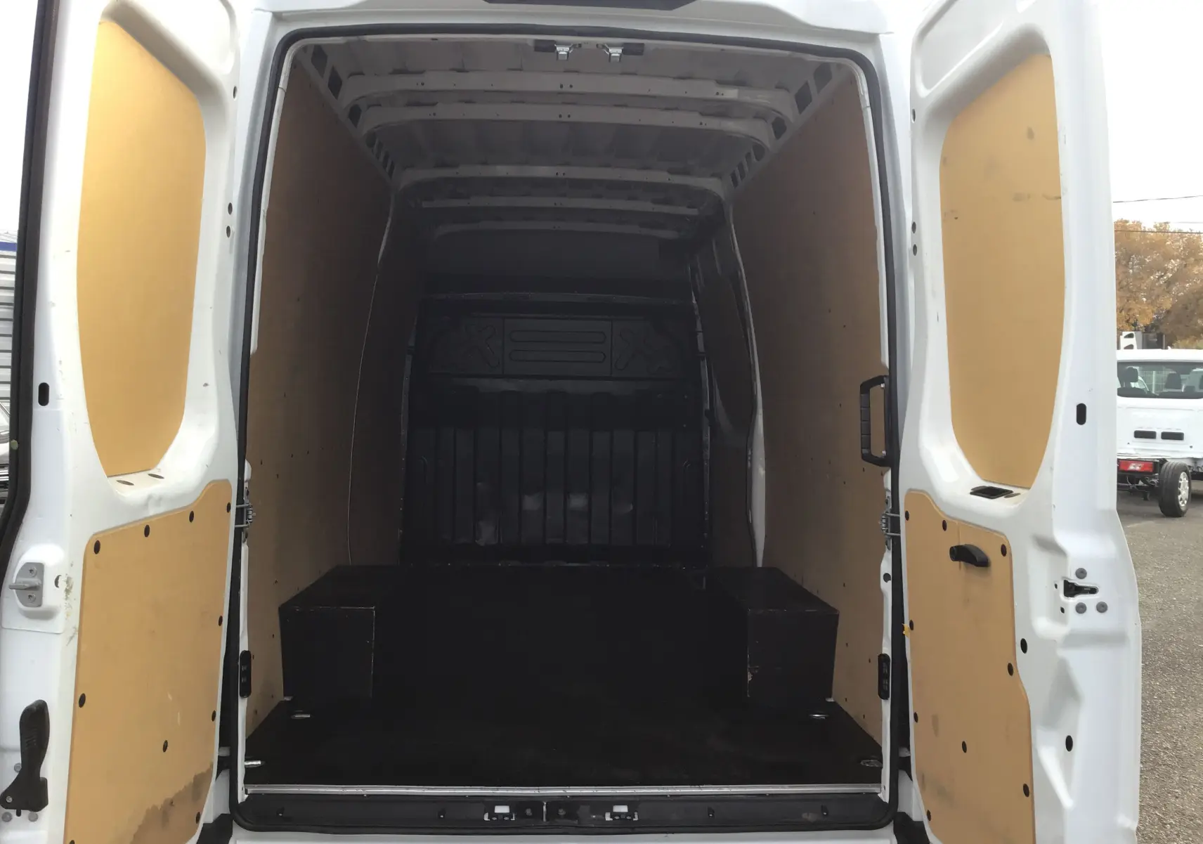 Vue arrière intérieure du fourgon Iveco Daily blanc 2022, montrant l'espace de chargement avec parois en bois clair.
