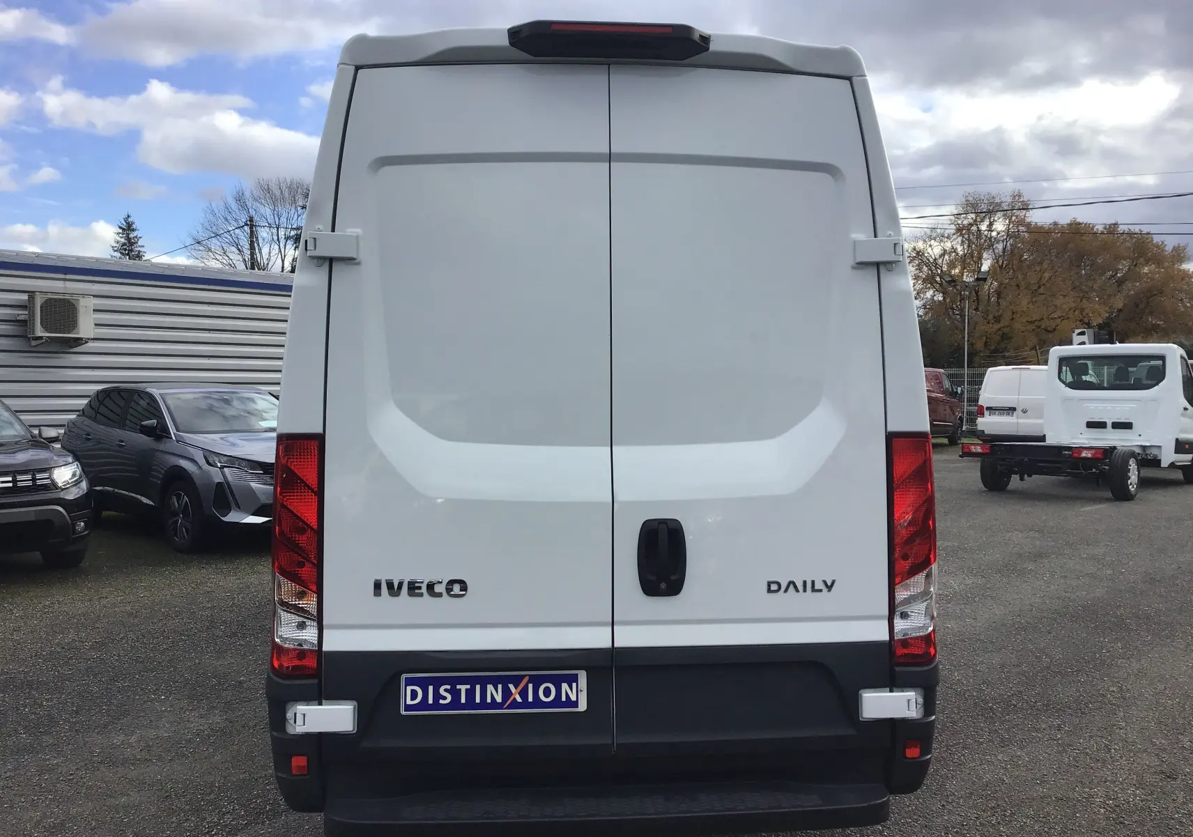 Vue arrière d'un fourgon Iveco Daily blanc 2022 avec portes battantes et feux rouges verticaux.