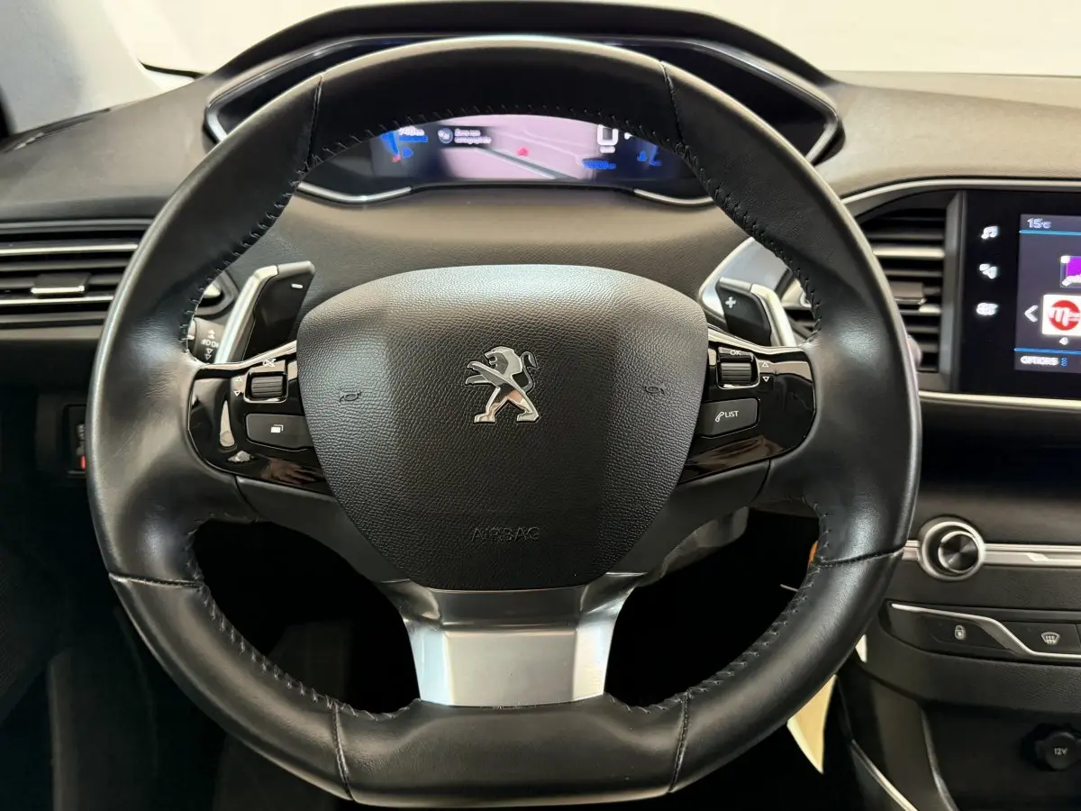 Gros plan sur le volant cuir noir du Peugeot 308 2021 avec tableau de bord numérique et écran tactile visible à droite.