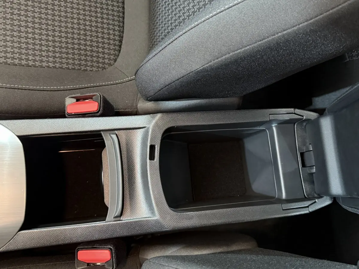 Vue plongeante sur la console centrale noire et les sièges tissu gris foncé de la Peugeot 308 blanche de 2021