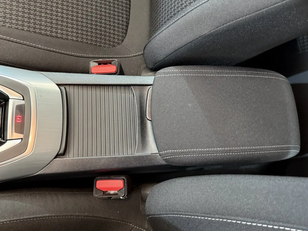 Vue rapprochée de la console centrale noire et des sièges tissu gris foncé de la Peugeot 308 blanche de 2021.