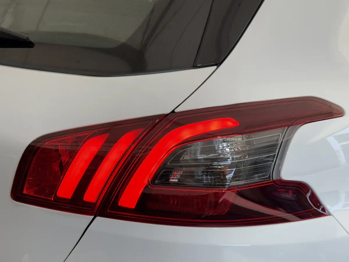 Feu arrière droit allumé d'une Peugeot 308 blanche, mettant en valeur ses lignes LED caractéristiques.