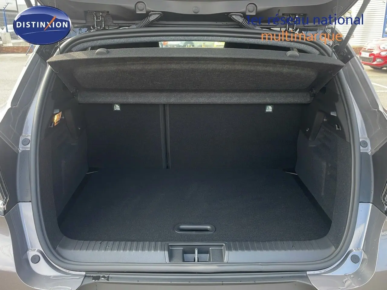 Coffre ouvert vu de l'arrière d'un Renault Captur gris Cassiopée métal avec toit noir, intérieur de coffre vide et propre.