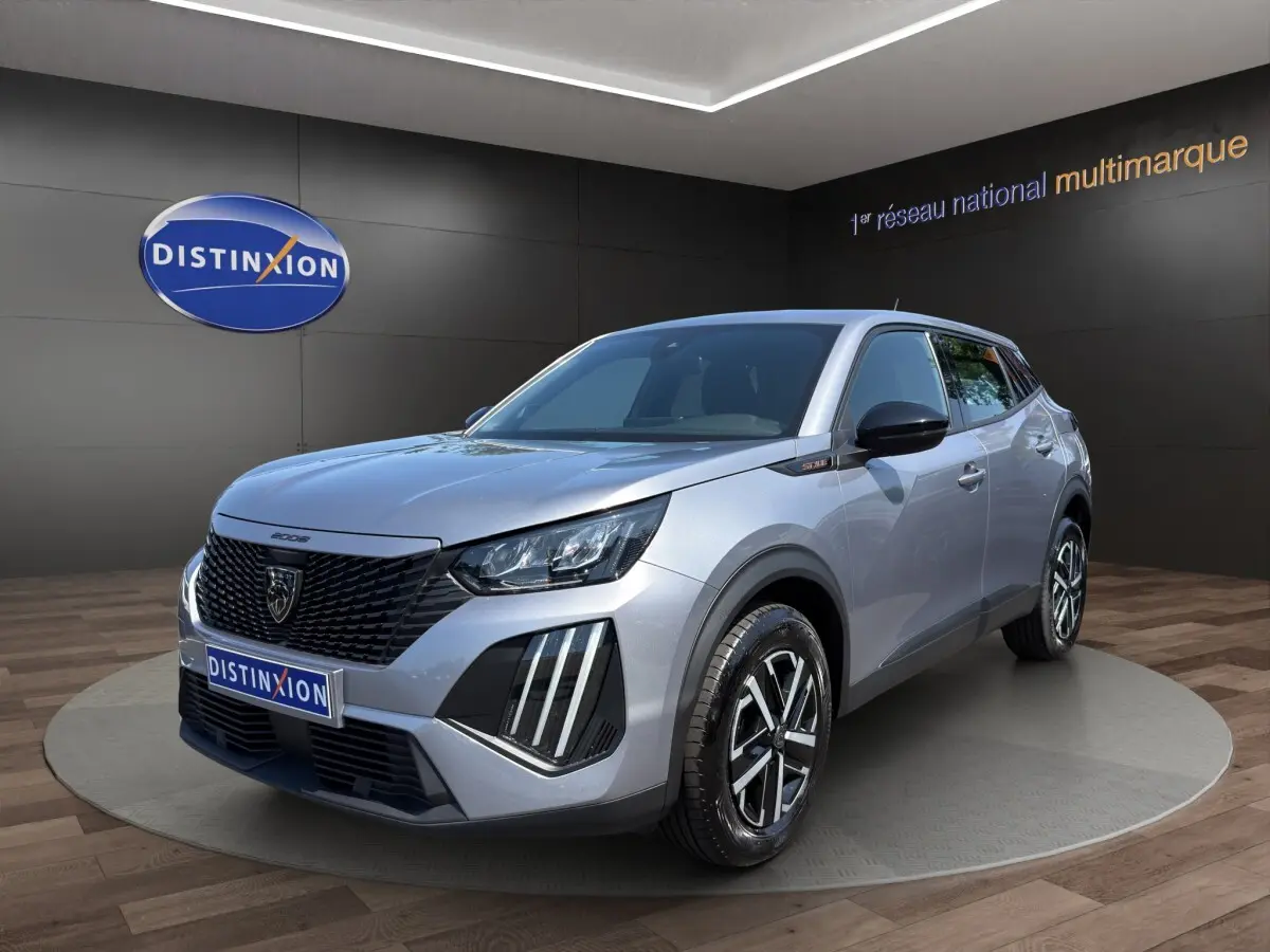 Peugeot 2008 Hybrid gris clair vue 3/4 avant droit, calandre noire et phares LED distinctifs.