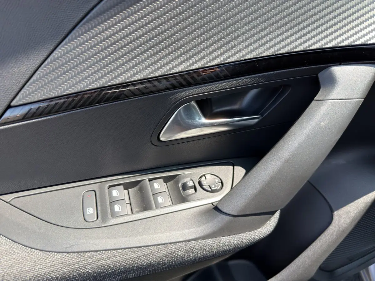 Détail de la porte côté conducteur du Peugeot 2008 gris clair, avec commandes électriques et poignée argentée.