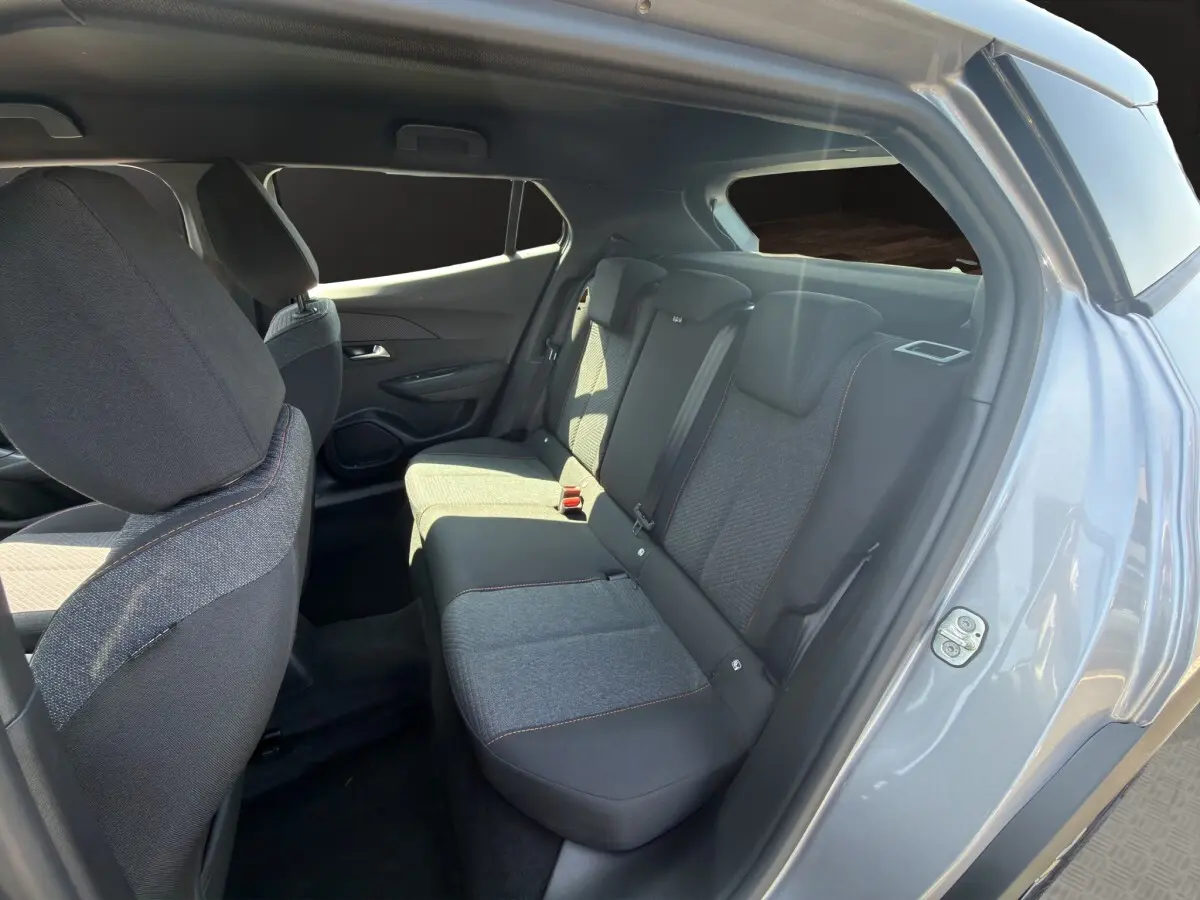 Vue intérieure côté arrière droit de la Peugeot 2008 Hybrid 145 gris clair, montrant la banquette et les sièges tissu.