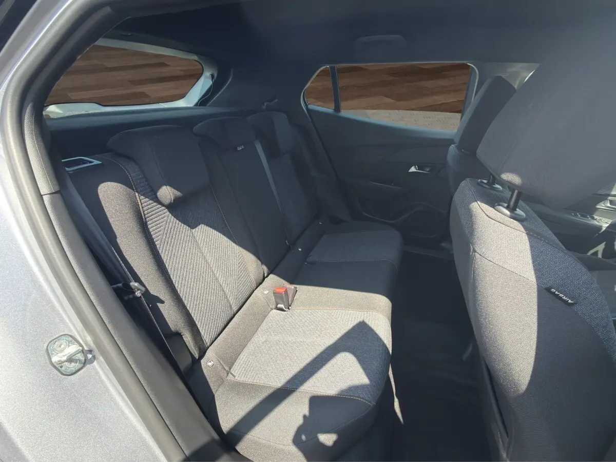 Vue intérieure côté arrière droit du Peugeot 2008 Hybrid 145 gris clair, montrant la banquette arrière en tissu.