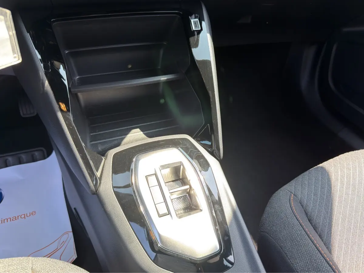 Vue intérieure centrée sur la console centrale noire brillante et la commande de boîte automatique du Peugeot 2008 gris clair.