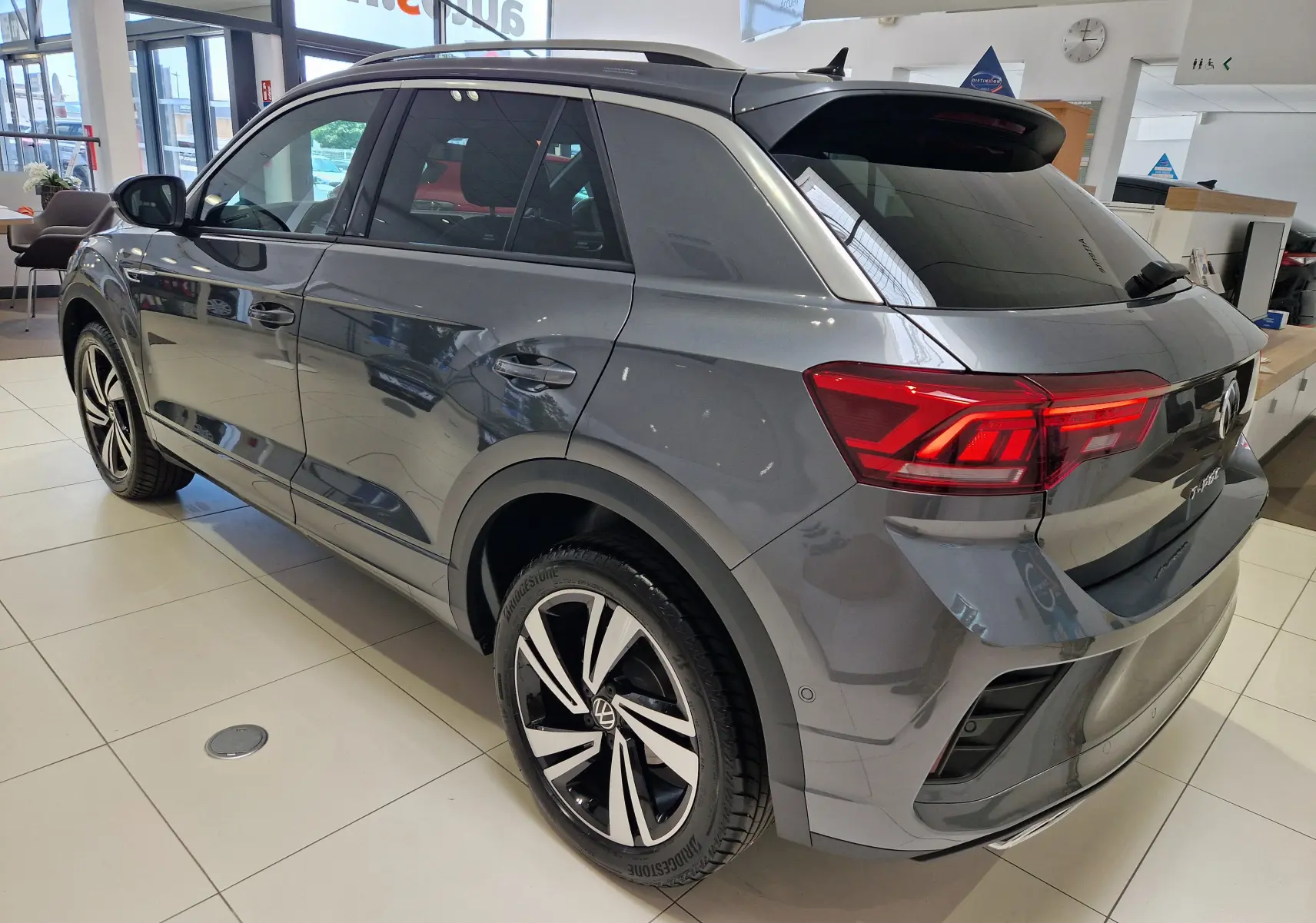 Volkswagen T-Roc gris Indium métal vu de trois quarts arrière droit, avec jantes alliage bicolores et feux arrière LED.