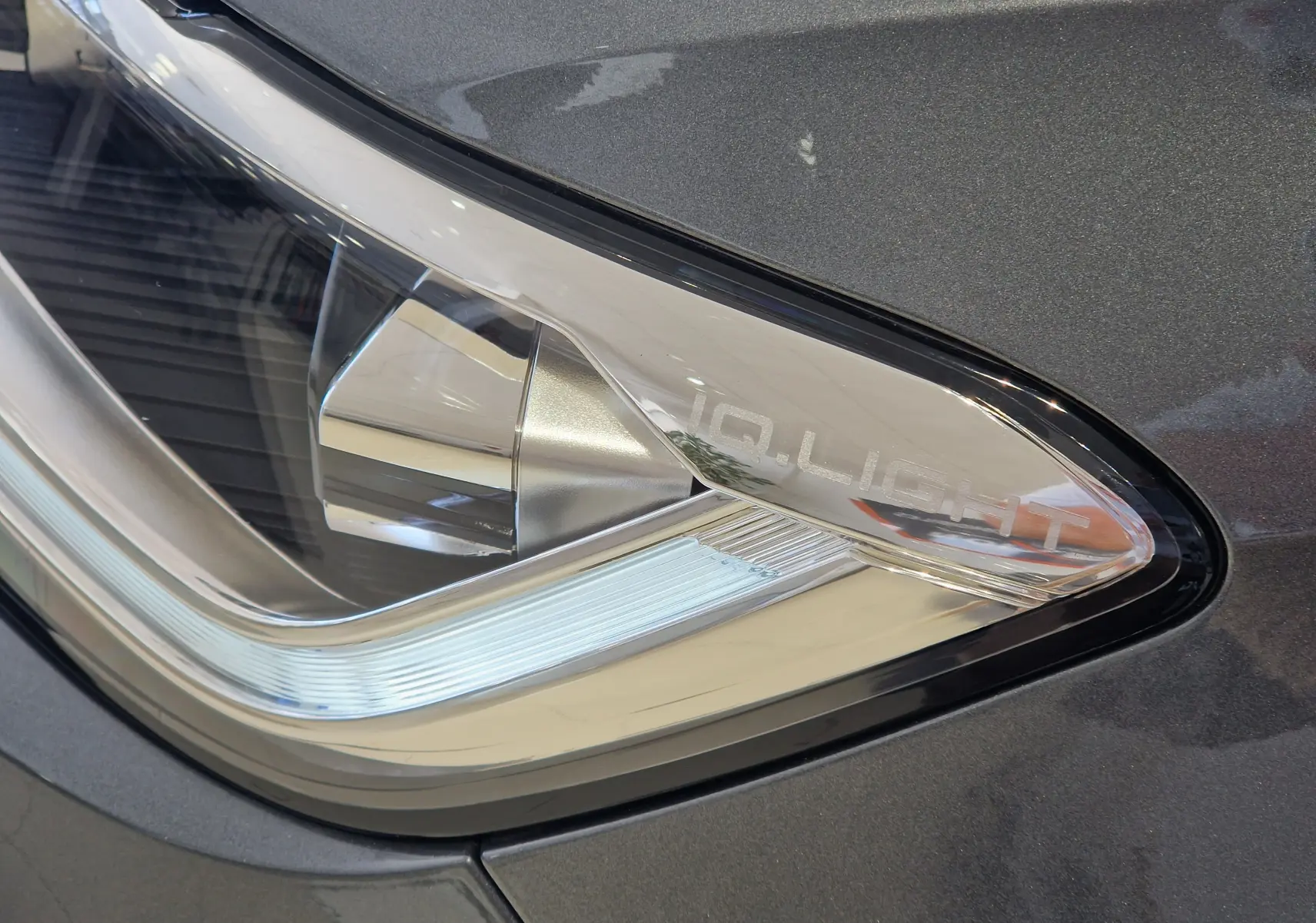 Gros plan sur le phare avant droit gris Indium Metal du Volkswagen T-Roc 2025 avec inscription IQ.LIGHT visible.