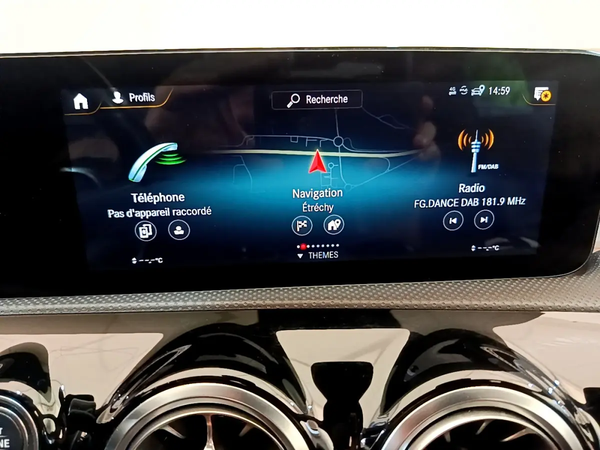 Écran tactile central affichant navigation et radio sur tableau de bord noir brillant d'une Mercedes CLA 200 d AMG Line.