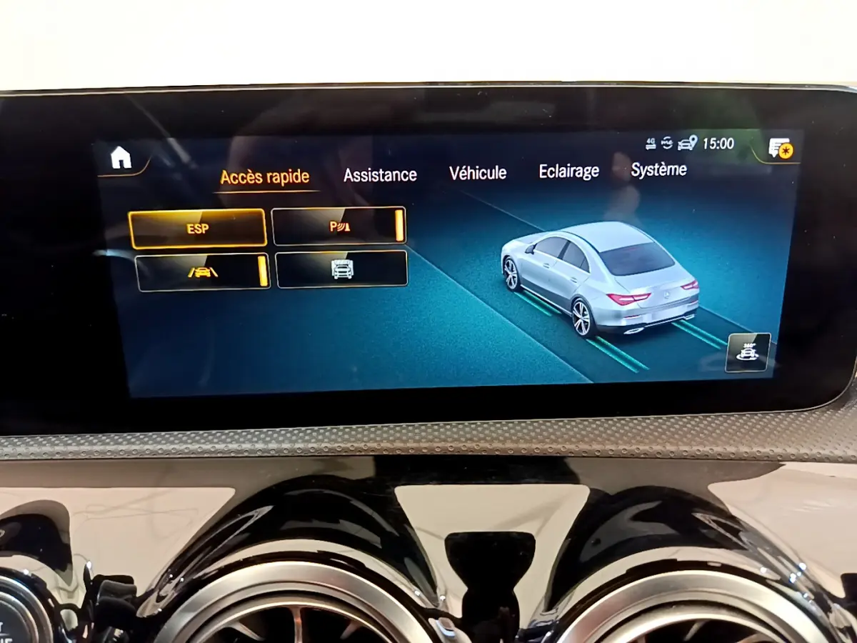 Écran tactile intérieur montrant l'assistance au stationnement avec une voiture grise vue de trois quarts arrière.