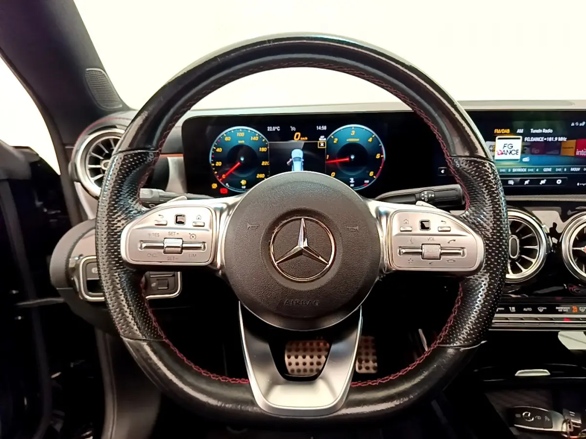 Vue intérieure centrée sur le volant cuir noir avec surpiqûres rouges de la Mercedes CLA 200 d AMG Line 2021.