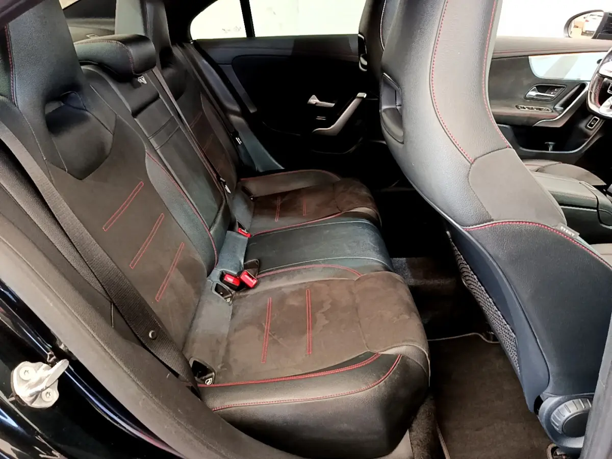 Vue intérieure côté gauche des sièges arrière noirs avec surpiqûres rouges de la Mercedes CLA 200 d AMG Line 2021.