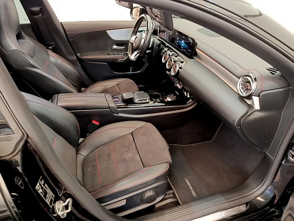 Vue intérieure côté passager de la Mercedes CLA 200 d AMG Line noire, sièges cuir et alcantara avec surpiqûres rouges.