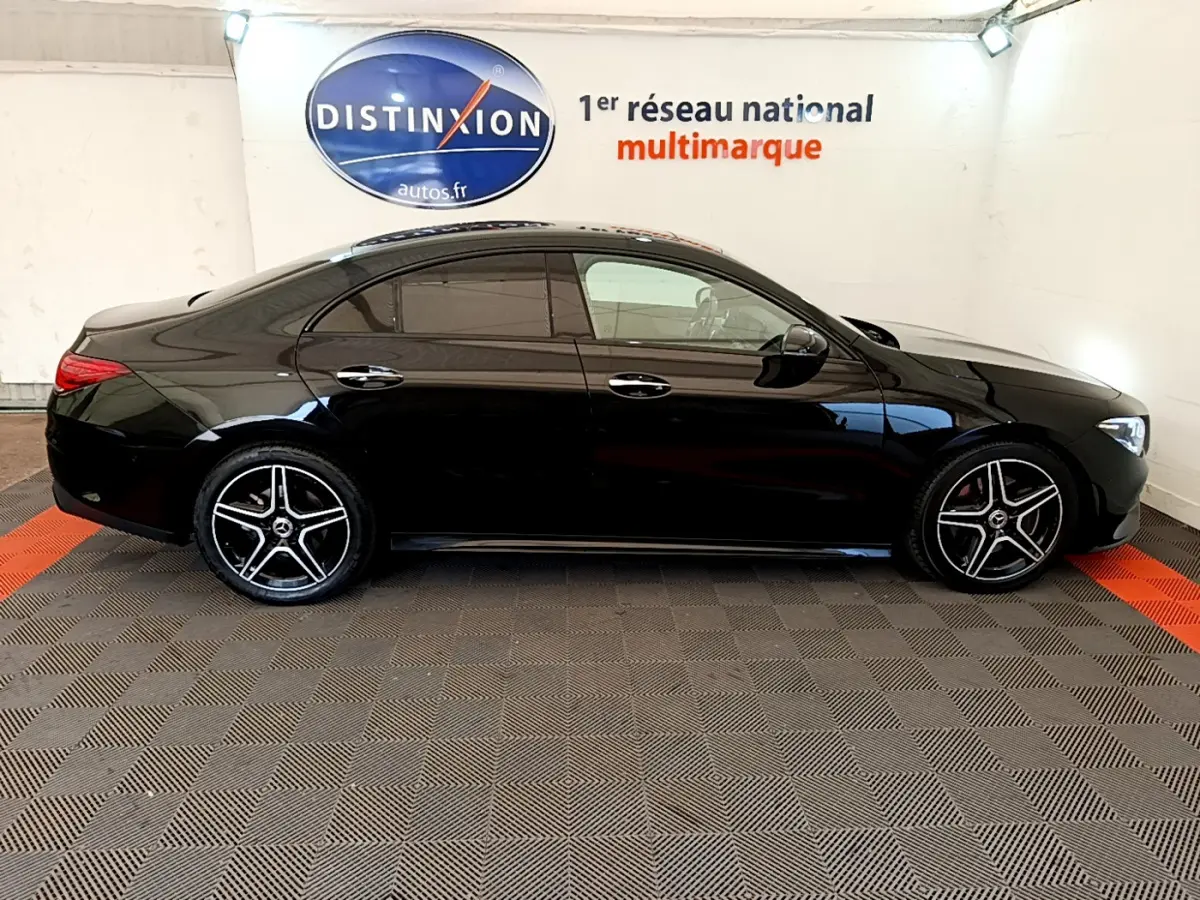 Profil côté gauche d'une Mercedes CLA 200 d AMG Line noire, avec jantes alliage et vitres teintées, en intérieur showroom.