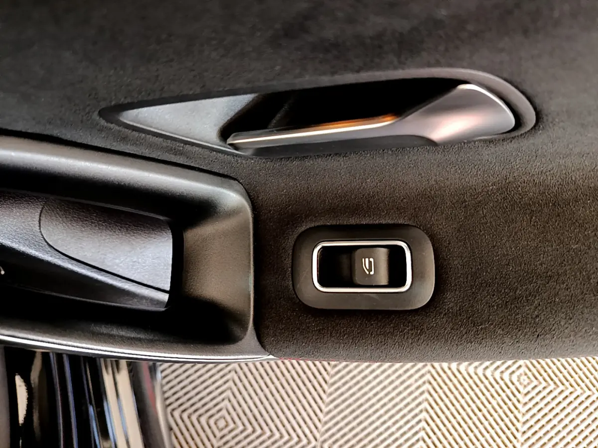 Gros plan sur la poignée intérieure et le bouton de verrouillage de la porte côté gauche d'une Mercedes CLA 200 d AMG Line noire.