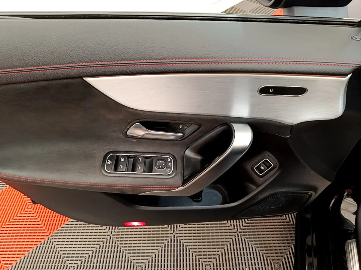 Vue rapprochée de la porte côté gauche noire avec surpiqûres rouges et insert aluminium de la Mercedes CLA 200 d AMG Line 2021.