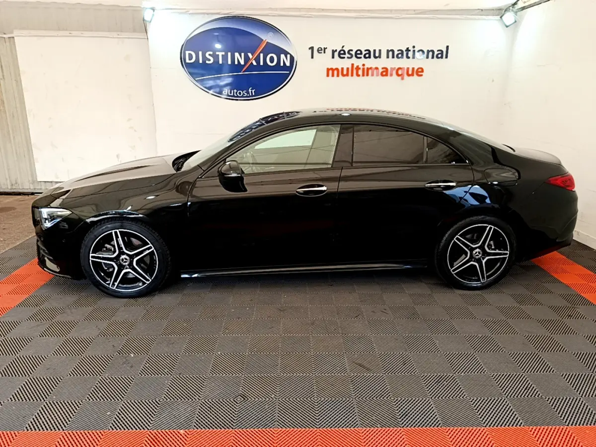 Profil côté gauche d'une Mercedes CLA 200 d AMG Line noire, avec jantes alliage et vitres teintées, en intérieur showroom.