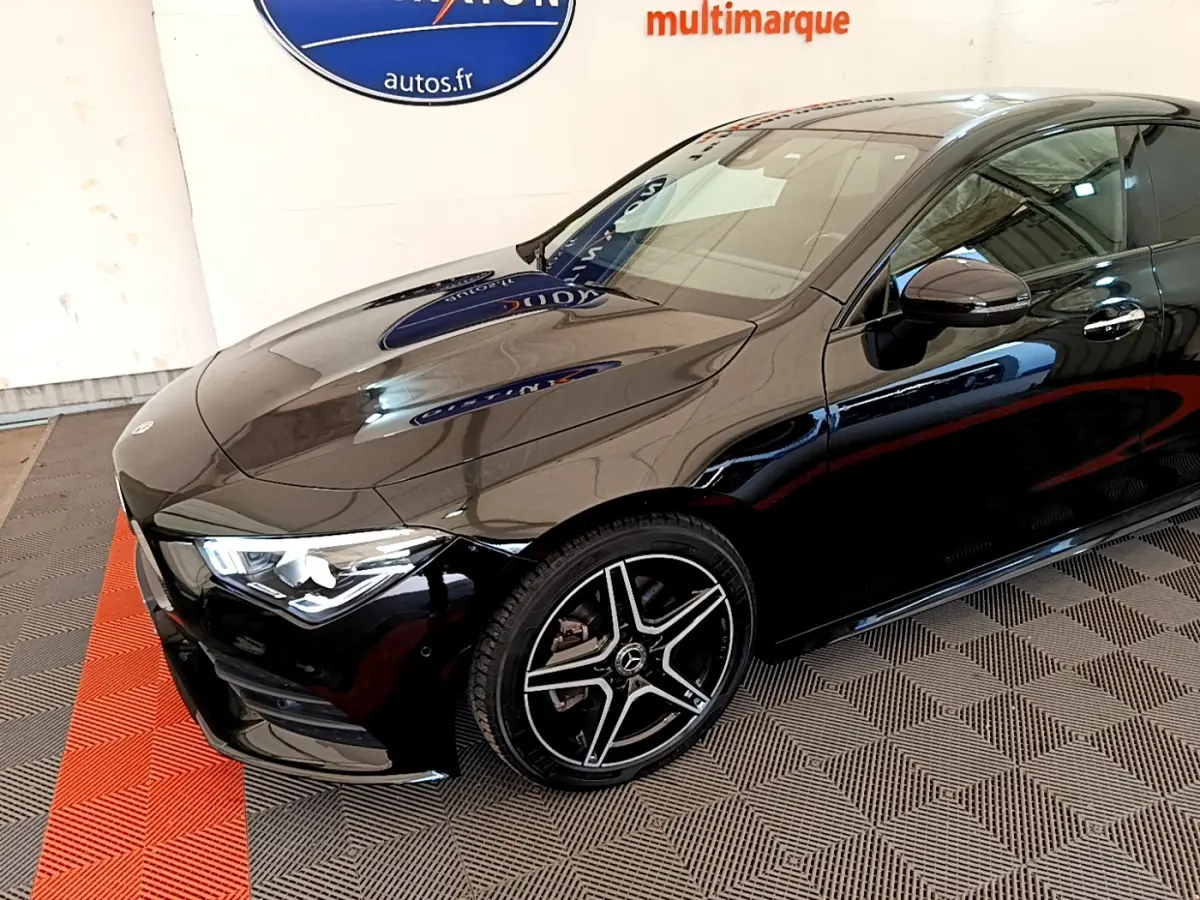 Vue 3/4 avant droit d'une Mercedes CLA 200 d AMG Line noire avec jantes alliage et phares LED allumés.