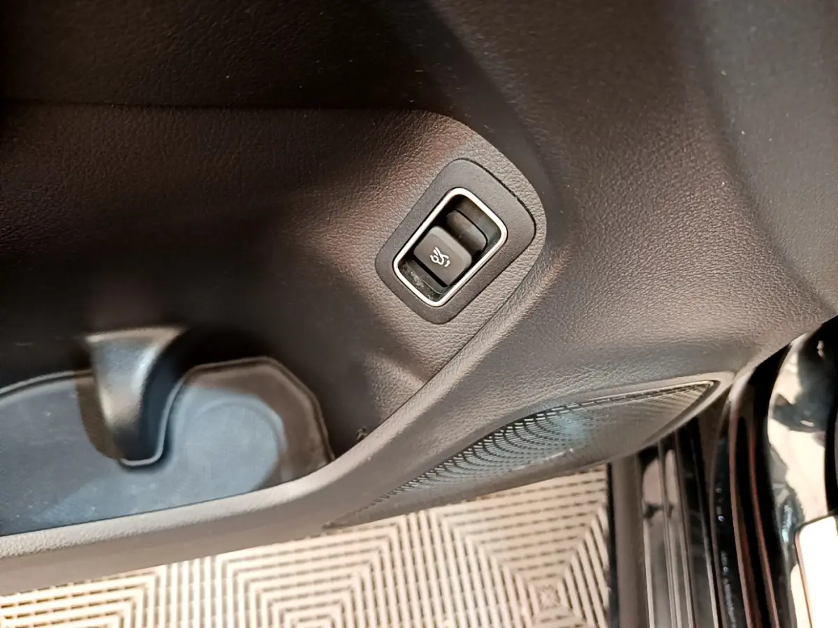 Gros plan sur le bouton de déverrouillage de coffre dans l'habitacle noir de la Mercedes CLA 200 d AMG Line 2021.