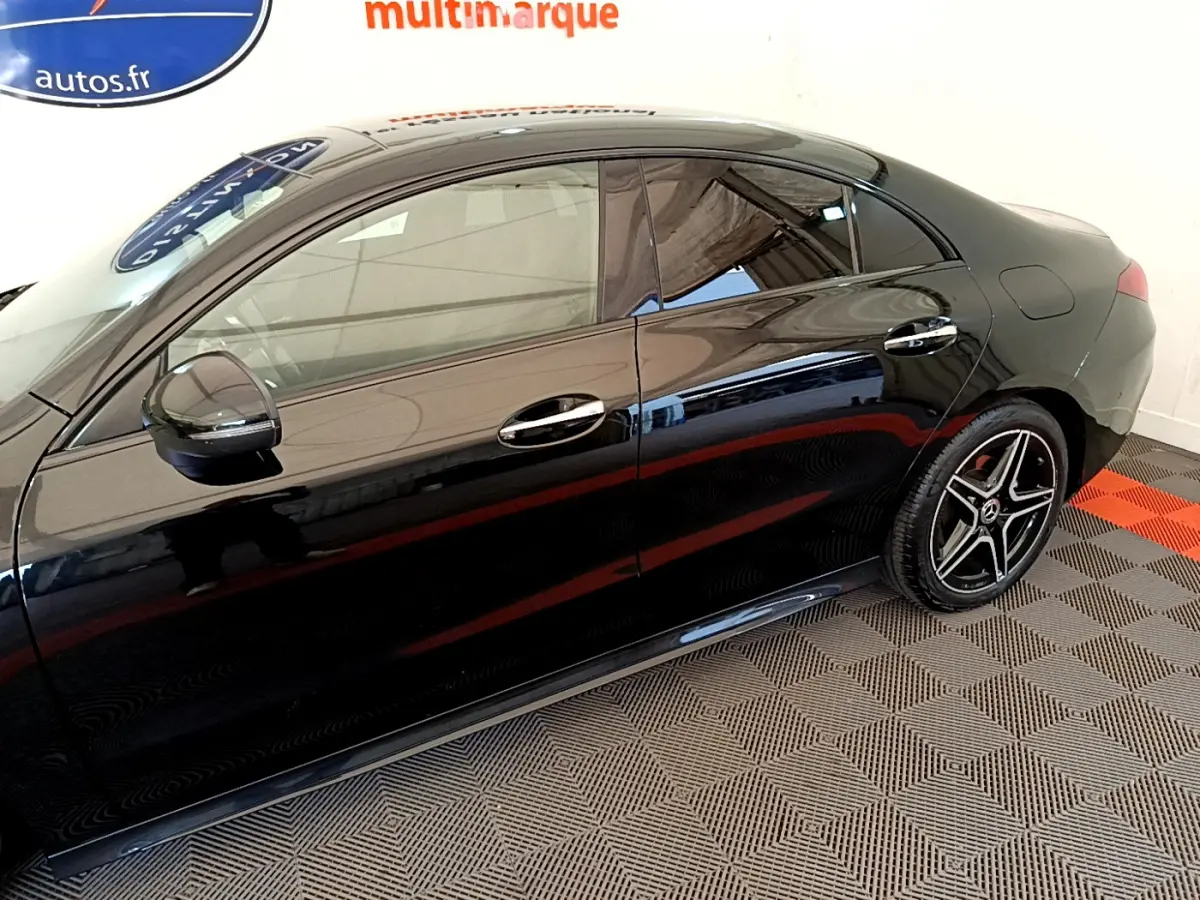 Profil côté gauche d'une Mercedes CLA 200 d AMG Line noire, avec jantes étoile et vitres teintées dans un showroom.