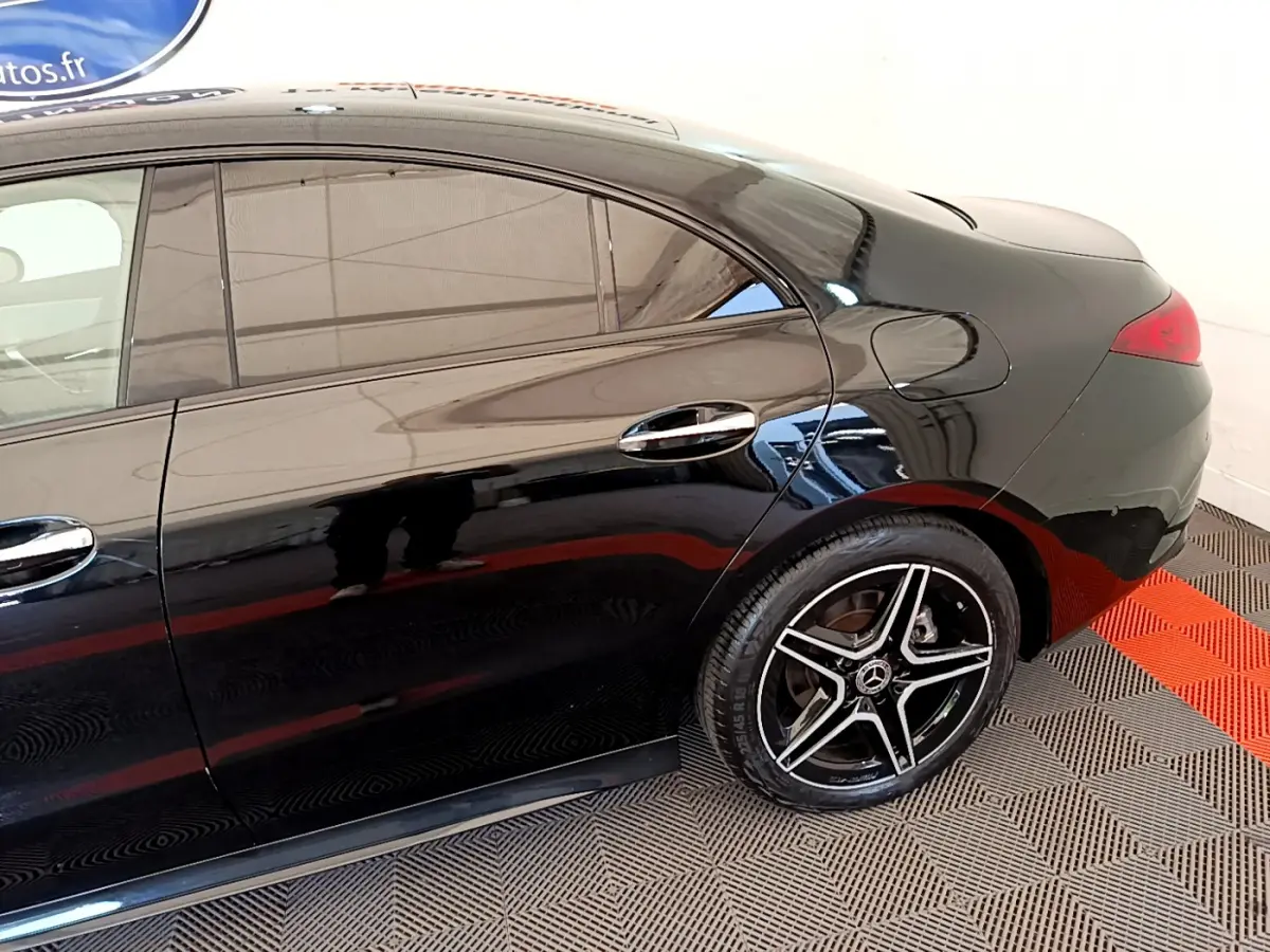 Vue latérale côté droit d'une Mercedes CLA 200 d AMG Line noire mettant en valeur la jante étoile AMG et les vitres teintées.