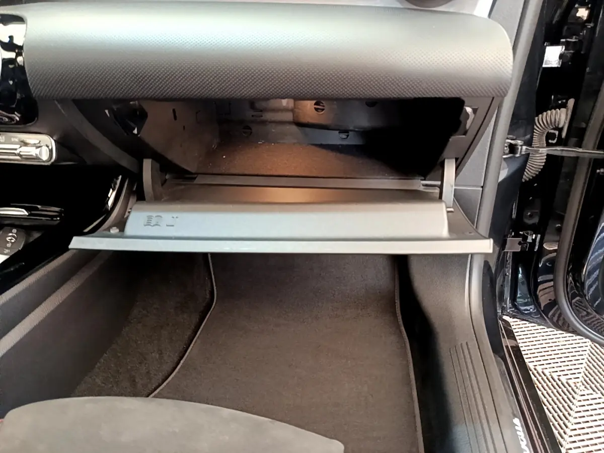 Gros plan sur la boîte à gants ouverte côté passager d'une Mercedes CLA 200 d AMG Line noire.