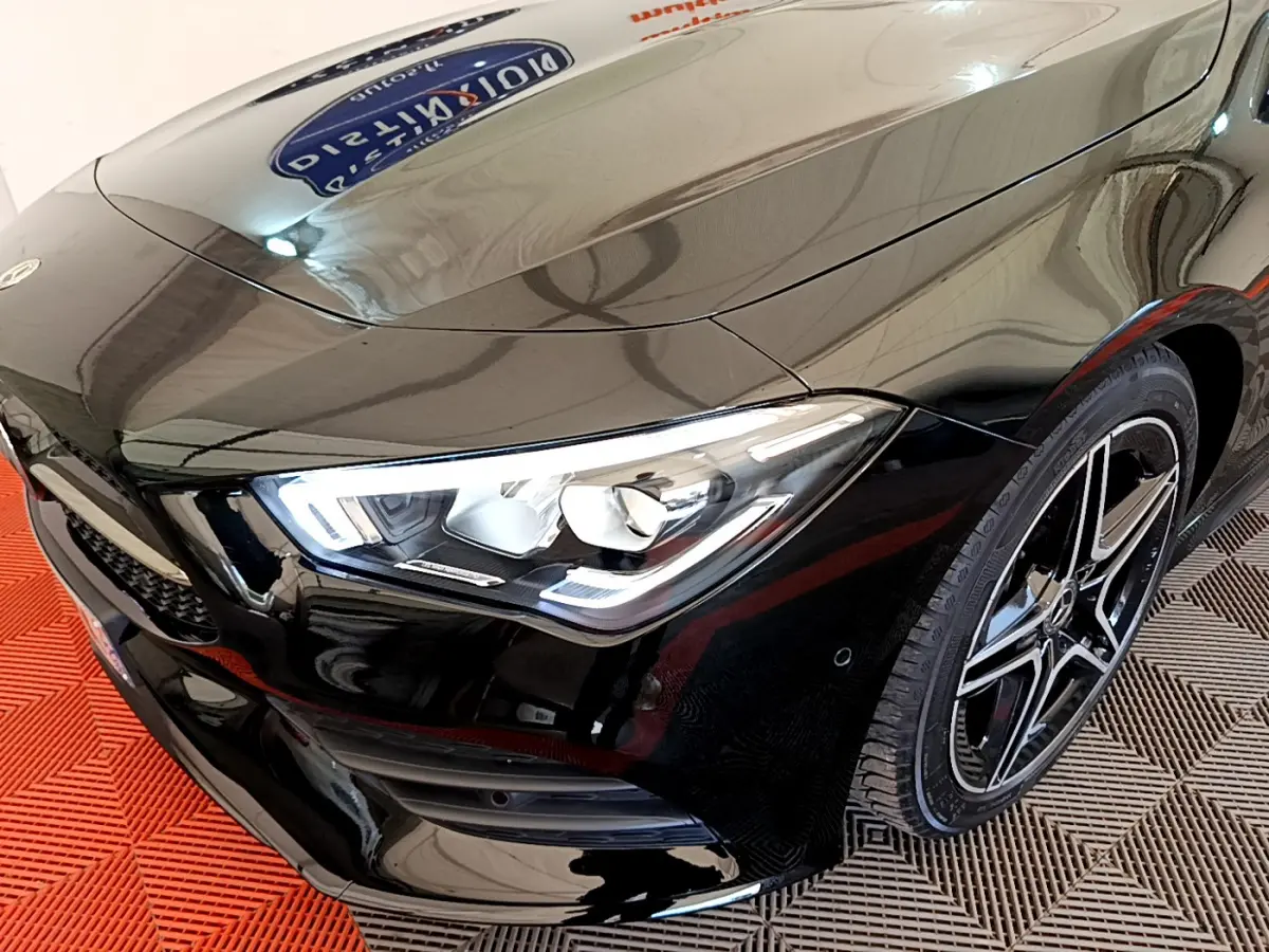 Vue 3/4 avant droit d'une Mercedes CLA 200 d AMG Line noire avec phares LED et jantes alliage distinctives.