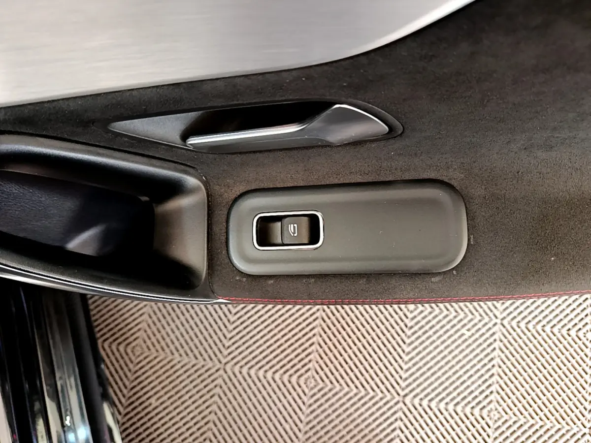 Bouton de commande de lève-vitre côté gauche sur la porte intérieure noire avec surpiqûres rouges d'une Mercedes CLA 200 d AMG Line 2021.