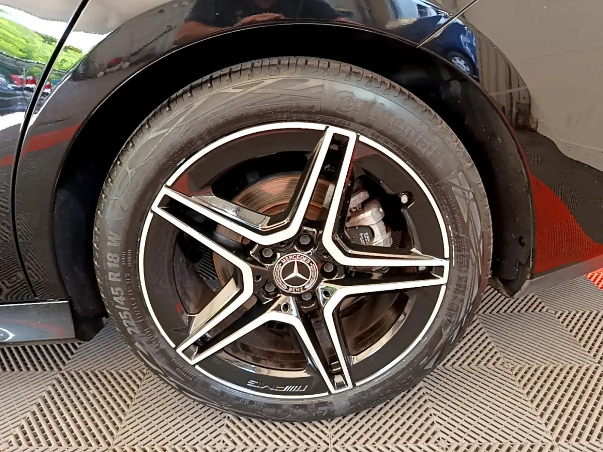 Gros plan sur la roue arrière droite noire d'une Mercedes CLA 200 d AMG Line 2021 avec jante AMG à cinq branches.