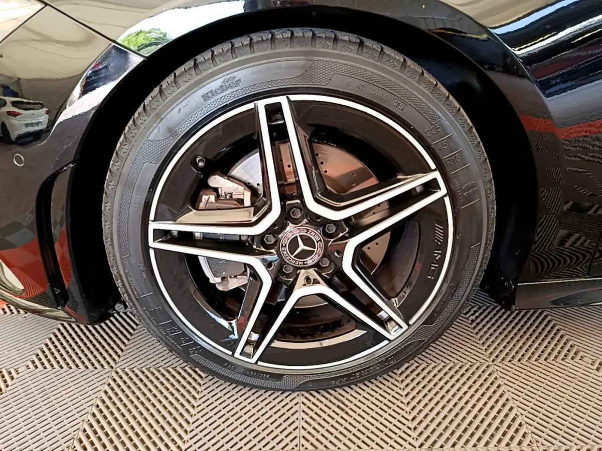 Gros plan sur la roue avant gauche noire d'une Mercedes CLA 200 d AMG Line avec jante étoile bicolore.