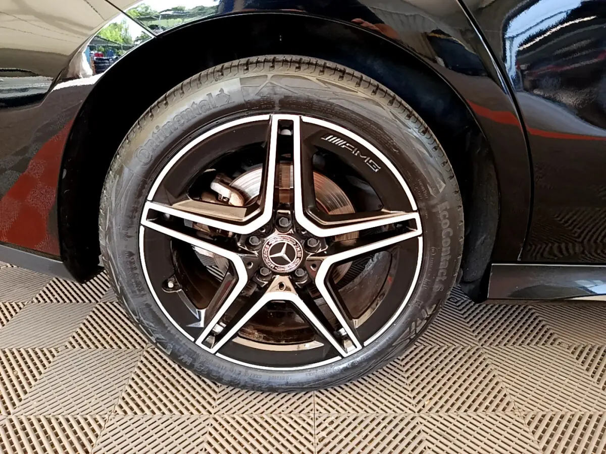 Gros plan sur la roue arrière droite noire d'une Mercedes CLA 200 d AMG Line avec jante AMG étoile cinq branches.