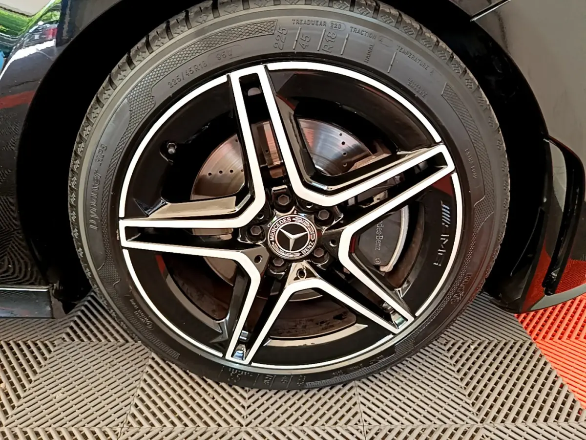 Gros plan sur la jante noire et argentée AMG à cinq branches du côté gauche d'une Mercedes CLA 200 d AMG Line noire de 2021.