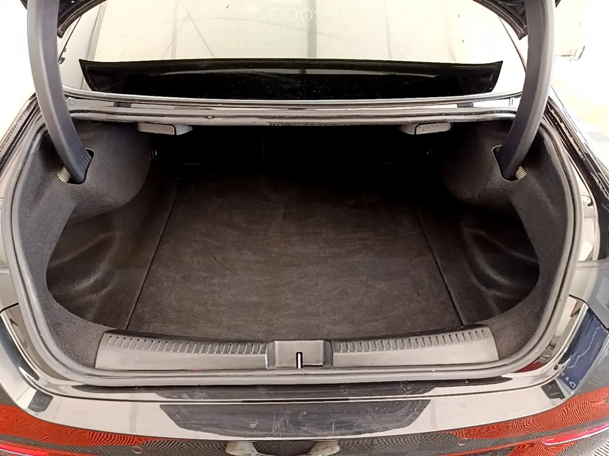 Coffre ouvert d'une Mercedes CLA 200 d AMG Line noir, vue arrière mettant en valeur l'espace de chargement.