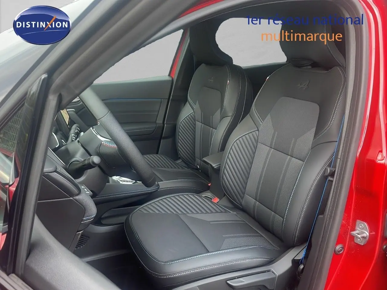 Vue intérieure côté conducteur du Renault Captur E-Tech hybride rouge passion, mettant en valeur les sièges en cuir noir avec surpiqûres bleues.