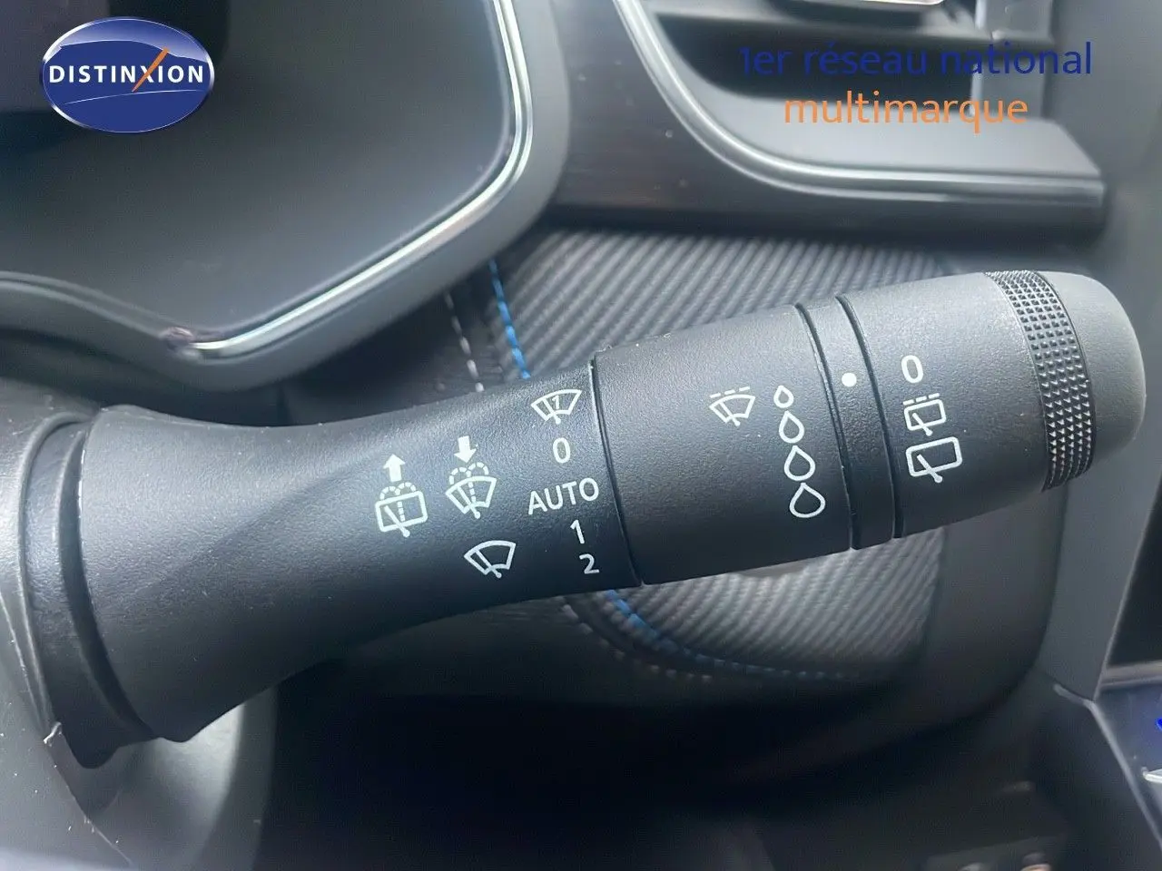 Gros plan sur la commande des essuie-glaces du Renault Captur E-Tech hybride 2025, intérieur noir avec surpiqûres bleues.
