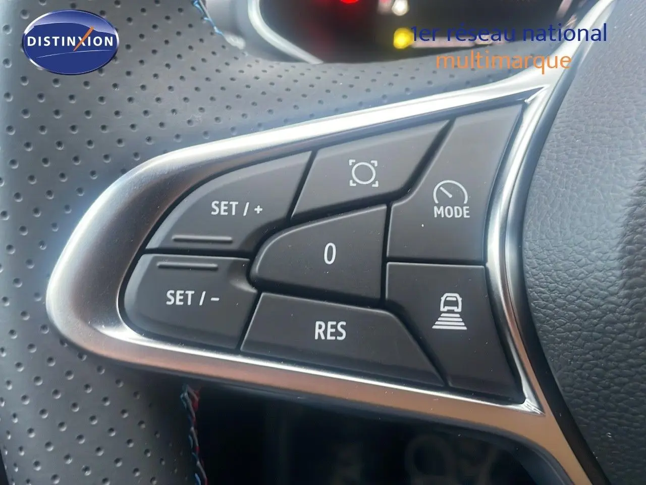 Gros plan sur les commandes au volant du Renault Captur E-Tech hybride 2025, avec finition cuir perforé noir.