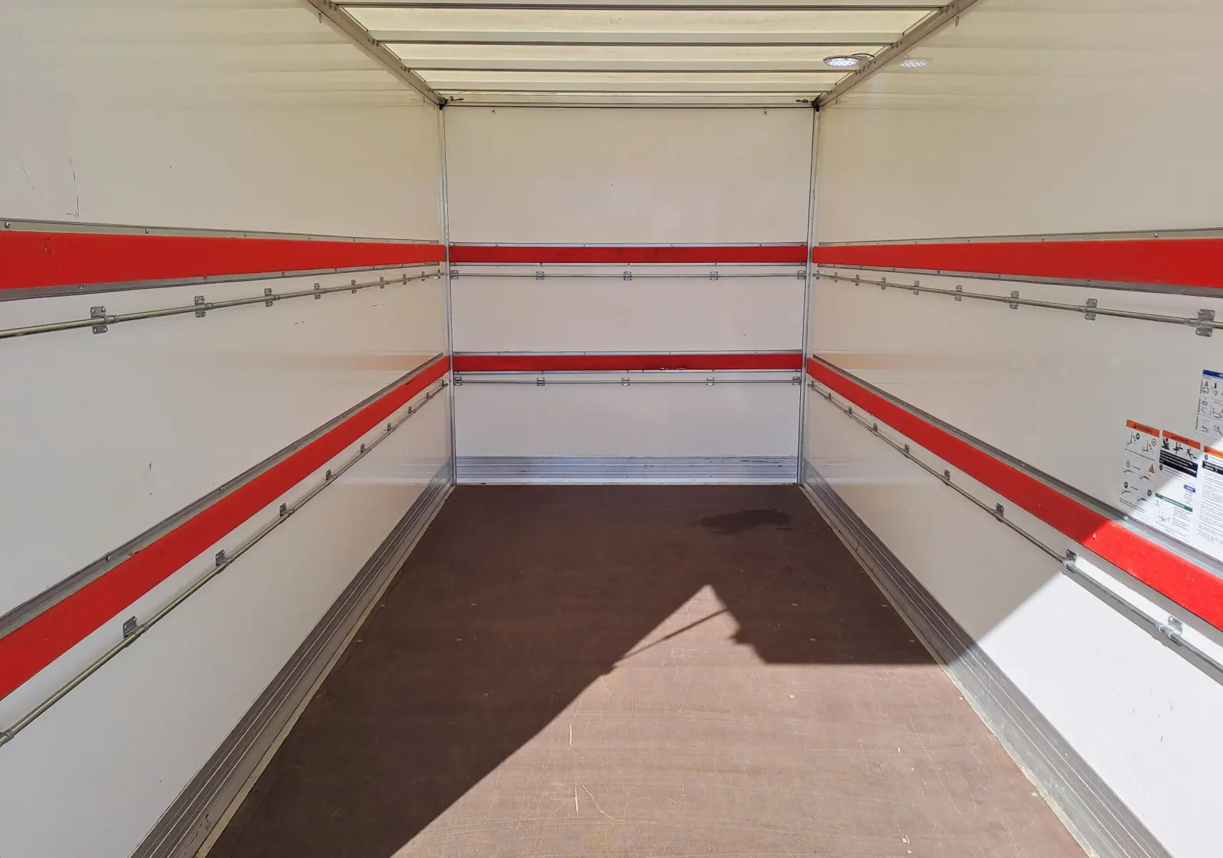 Intérieur de la benne blanche du Nissan Interstar Châssis Cabine L3H1 2024, vue de l'arrière vers l'avant avec bandes rouges.