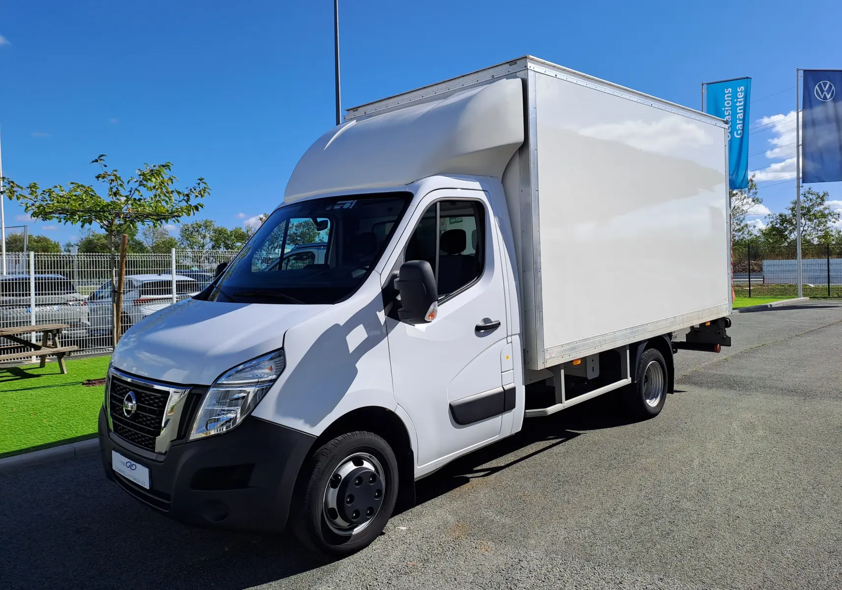 Nissan Interstar châssis cabine blanc vu en 3/4 avant droit sur parking extérieur sous ciel bleu.