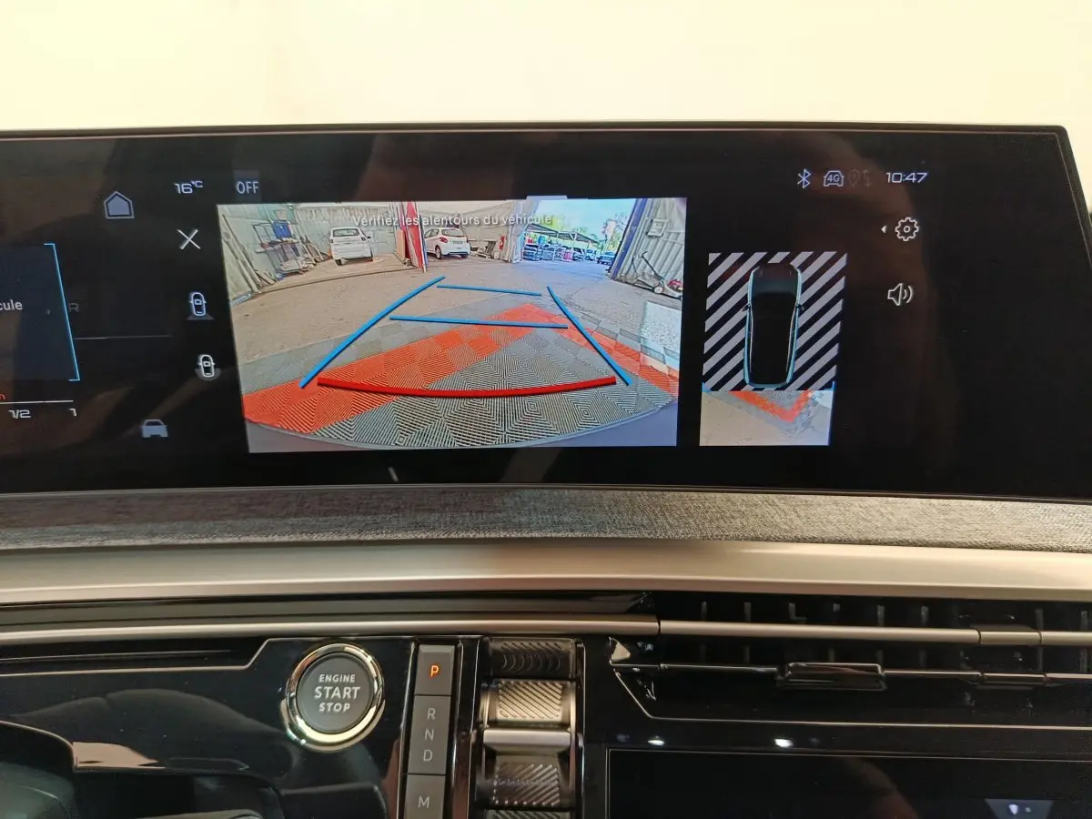 Vue rapprochée de l'écran tactile central du Peugeot 3008 blanc 2025 affichant la caméra de recul et l'aide au stationnement.