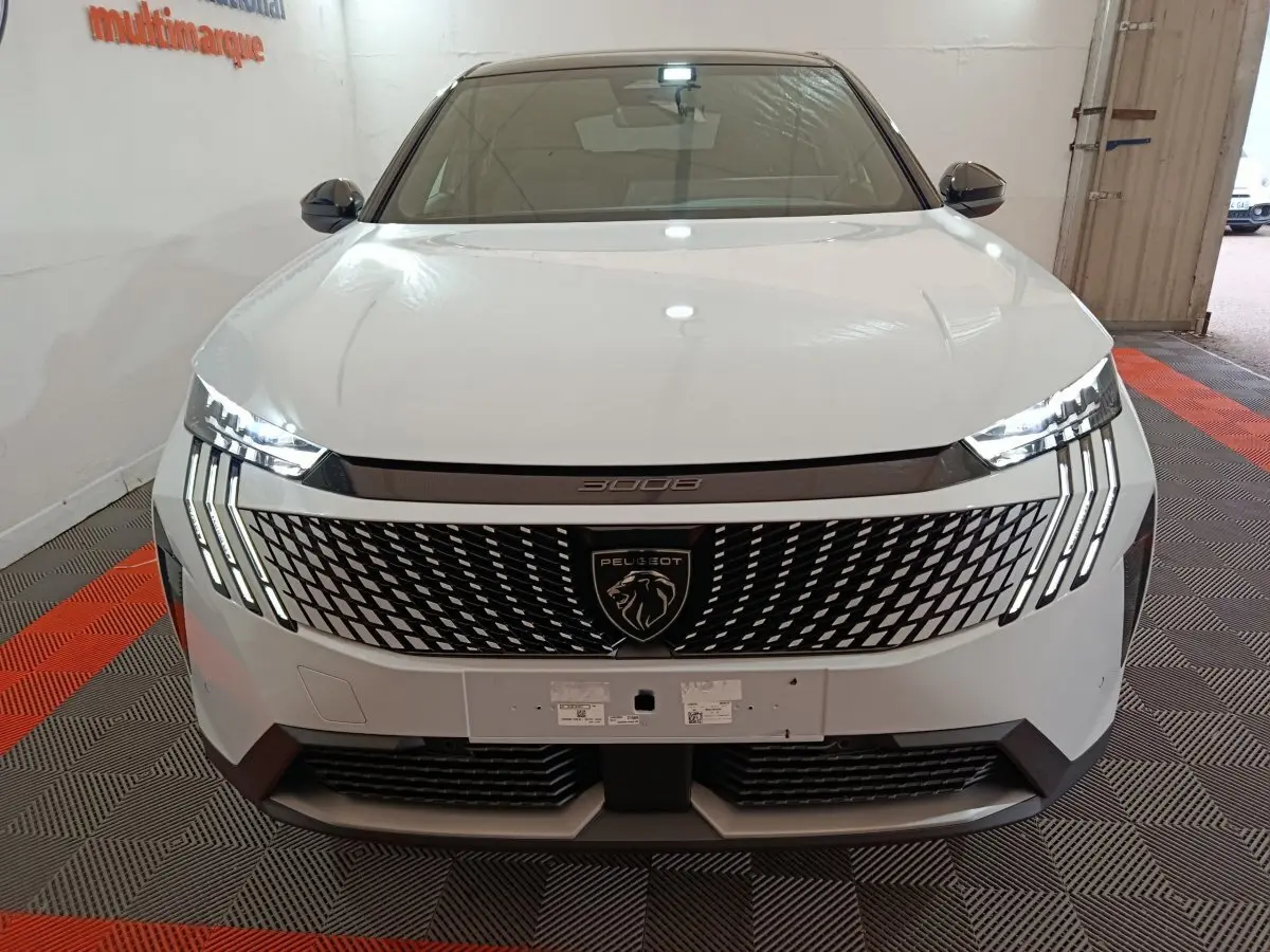 Vue frontale du Peugeot 3008 blanc 2025 avec calandre distinctive et feux LED en griffes allumés.