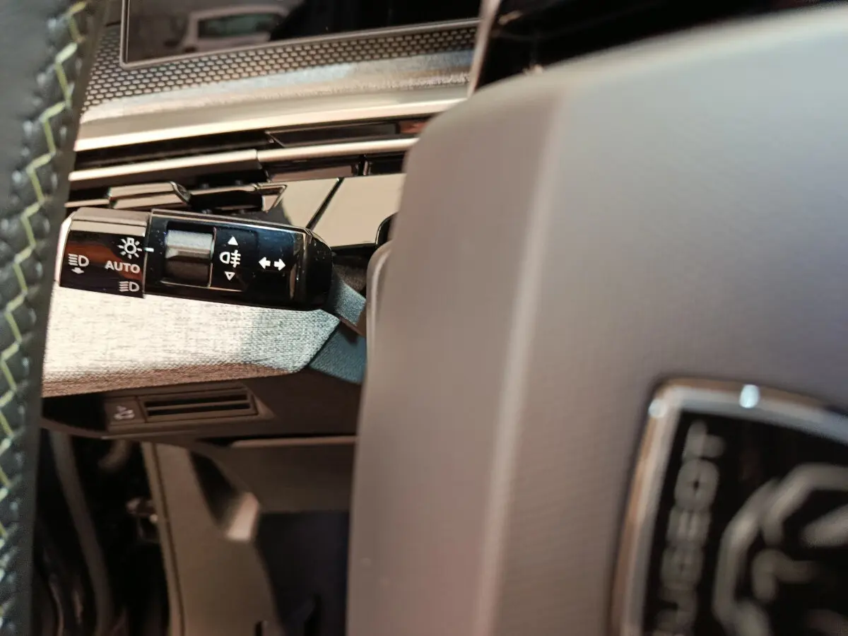 Gros plan sur la manette des feux et clignotants à gauche du volant d'un Peugeot 3008 blanc 2025.