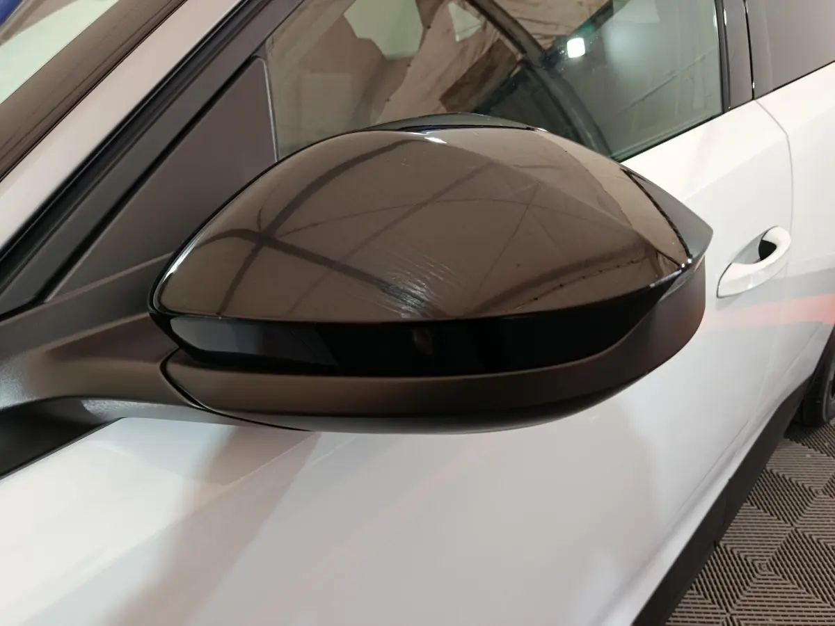 Rétroviseur noir brillant côté gauche du Peugeot 3008 blanc, avec porte et poignée visibles en arrière-plan.